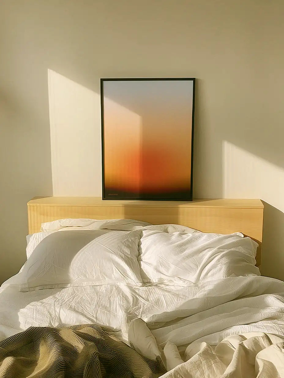 Minimalistyczna, oprawiona abstrakcyjna sztuka z płynnym gradientem przechodzącym od ciepłego pomarańczowego do miękkiego beżu, umieszczona w smukłej czarnej ramie.